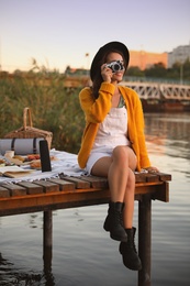 Young woman taking picture with camera on pier at picnic