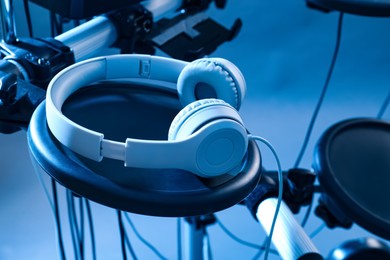 Photo of Modern electronic drum kit with headphones on light background, toned in blue. Musical instrument