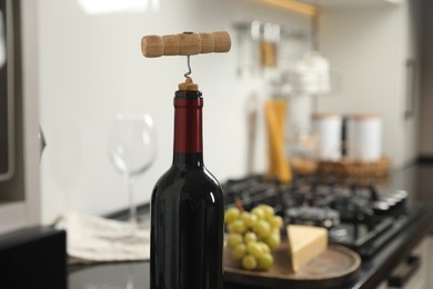 Wine bottle with corkscrew in kitchen, closeup. Space for text