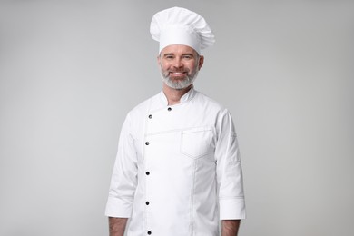 Photo of Happy chef in uniform on grey background