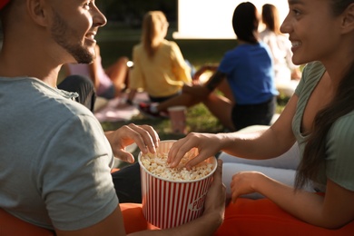 Photo of Young couple with popcorn watching movie in open air cinema, closeup. Space for text