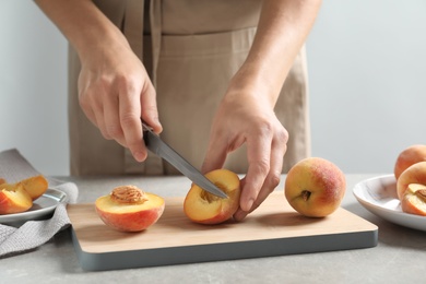 Photo of Woman cutting fresh sweet peaches on table