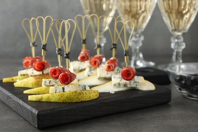 Photo of Tasty canapes with pears, blue cheese and prosciutto on grey table, closeup