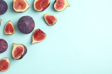 Photo of Delicious ripe figs on turquoise background, flat lay. Space for text