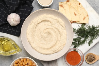 Photo of Bowl with delicious hummus and different ingredients on light grey table, flat lay