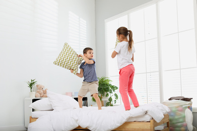 Photo of Happy children having pillow fight in bedroom