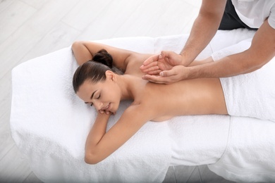 Photo of Relaxed woman receiving back massage in wellness center