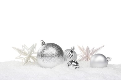 Beautiful silver Christmas balls and decorative snowflakes on snow against white background