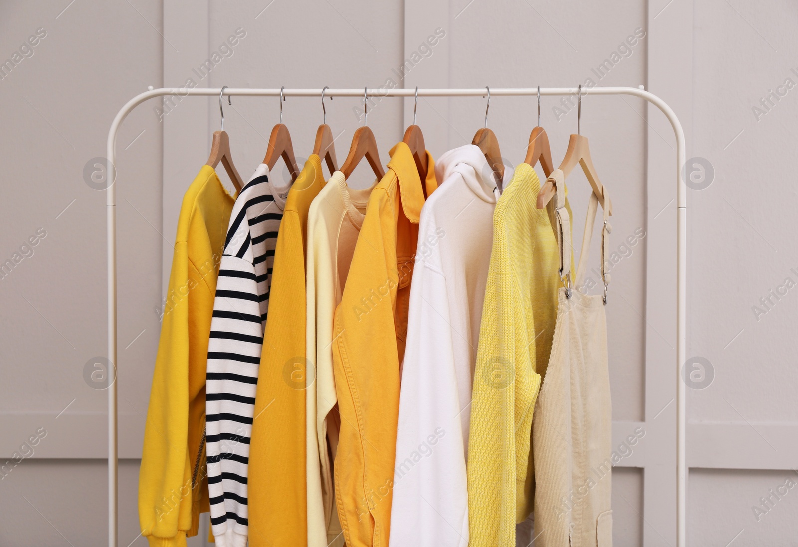 Photo of Rack with stylish women's clothes near light wall