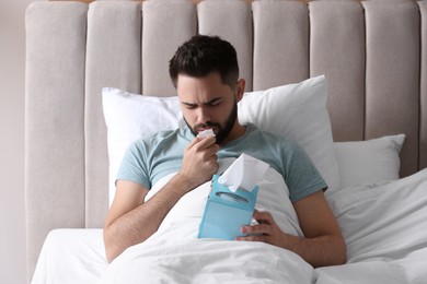 Man suffering from runny nose in bed