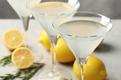 Photo of Martini glasses of refreshing cocktail, lemon and rosemary on light grey table, closeup