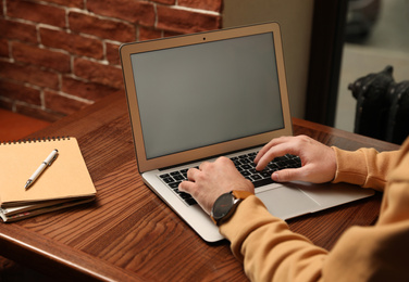 Photo of Male blogger working with laptop at table in cafe, closeup