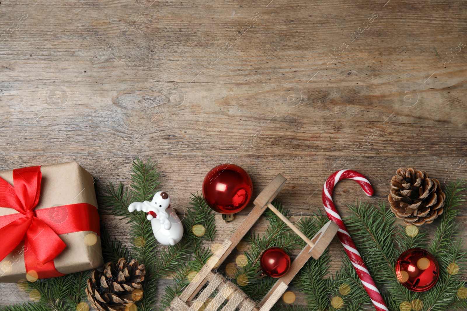 Photo of Christmas greeting card with space for text. Flat lay composition of fir tree branches and festive decor on wooden background