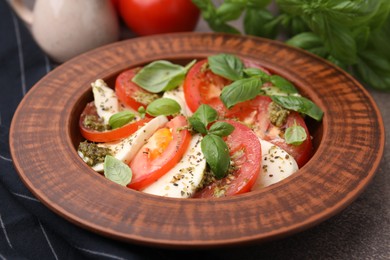 Plate of delicious Caprese salad with pesto sauce on table, closeup