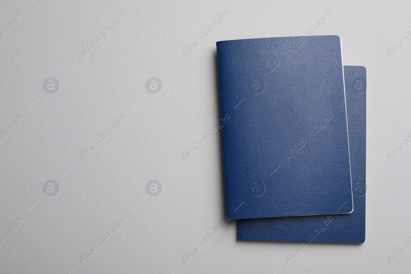 Photo of Blank blue passports on grey background, flat lay with space for text