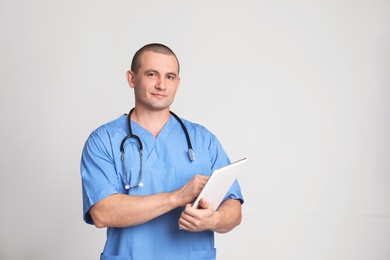 Portrait of medical assistant with stethoscope and tablet on color background. Space for text