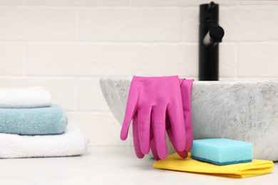 Photo of Sponge, rag and rubber gloves near sink in bathroom. Space for text