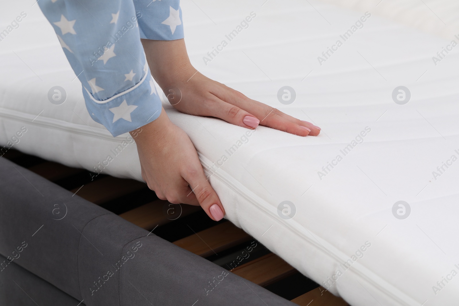 Photo of Woman putting new soft mattress on bed, closeup