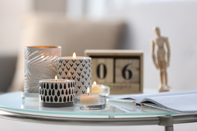 Photo of Burning candles in holders and notebook on white table indoors
