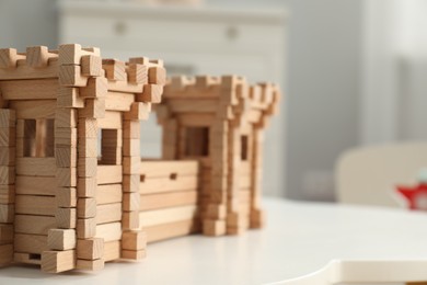 Photo of Wooden fortress on white table indoors, space for text. Children's toy