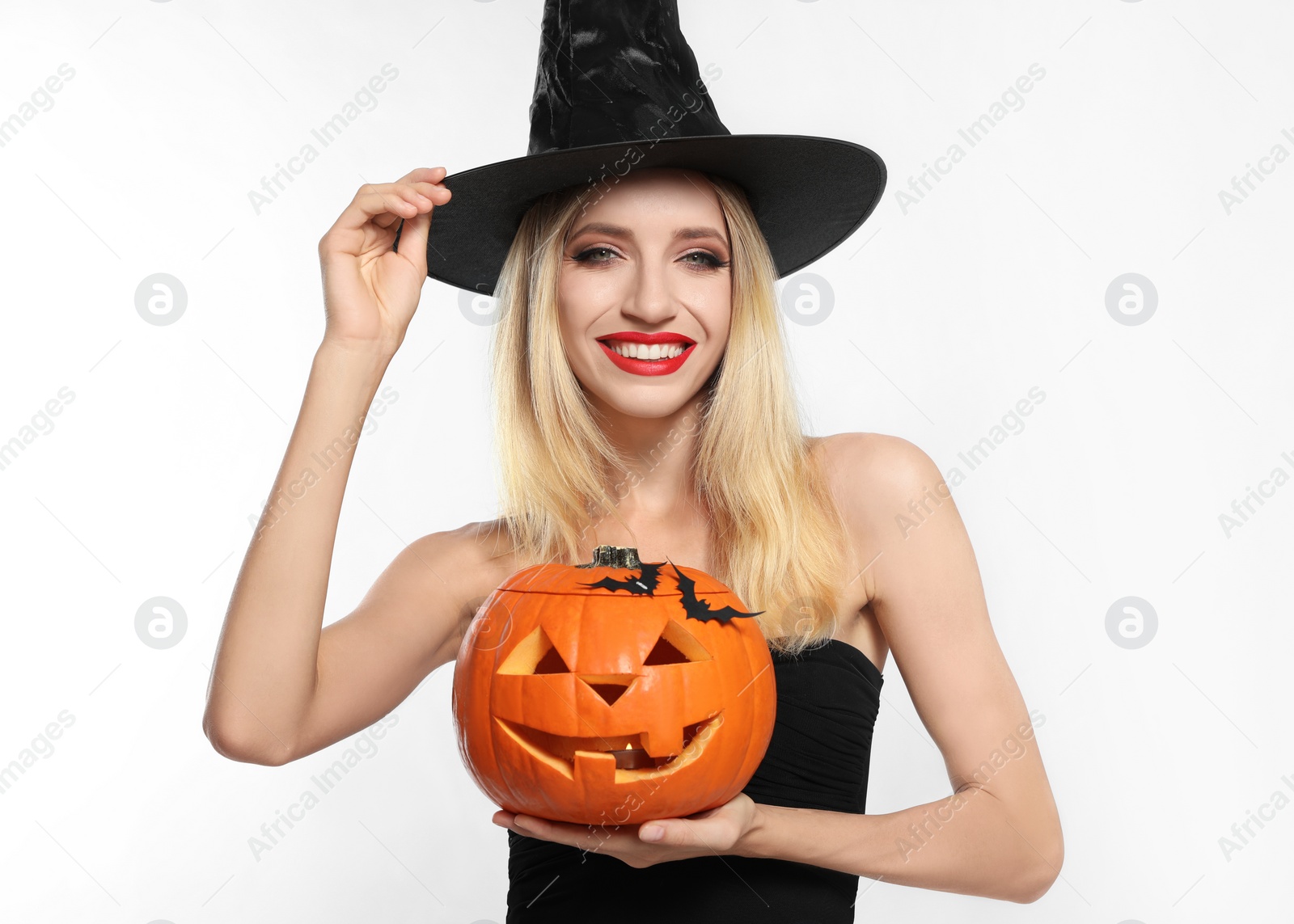 Photo of Beautiful woman in witch costume with jack o'lantern on white background. Halloween party