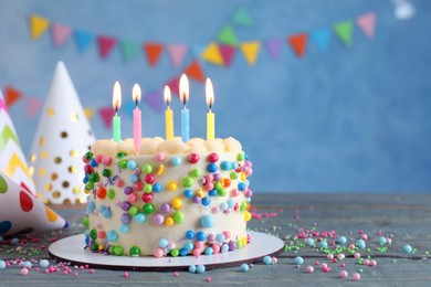 Photo of Cute bento cake with tasty cream and burning candles on light blue wooden table. Space for text