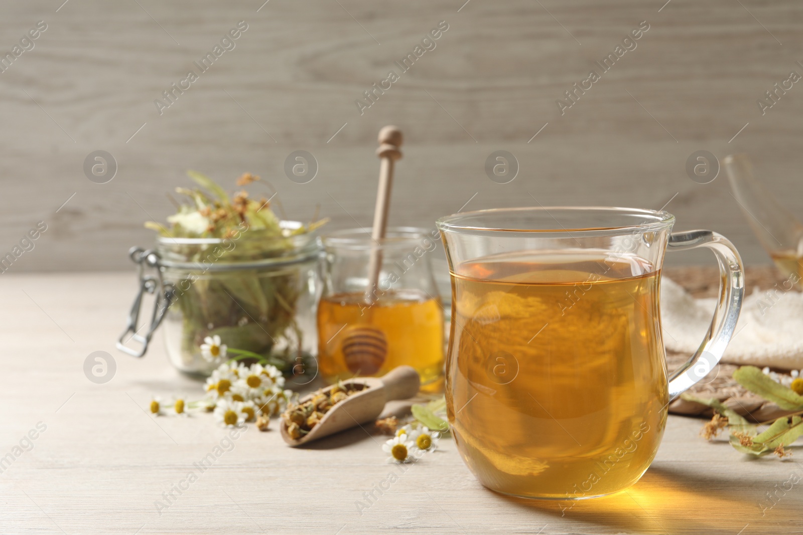 Photo of Freshly brewed tea and dried herbs on white wooden table. Space for text