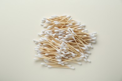 Heap of wooden cotton buds on beige background, flat lay