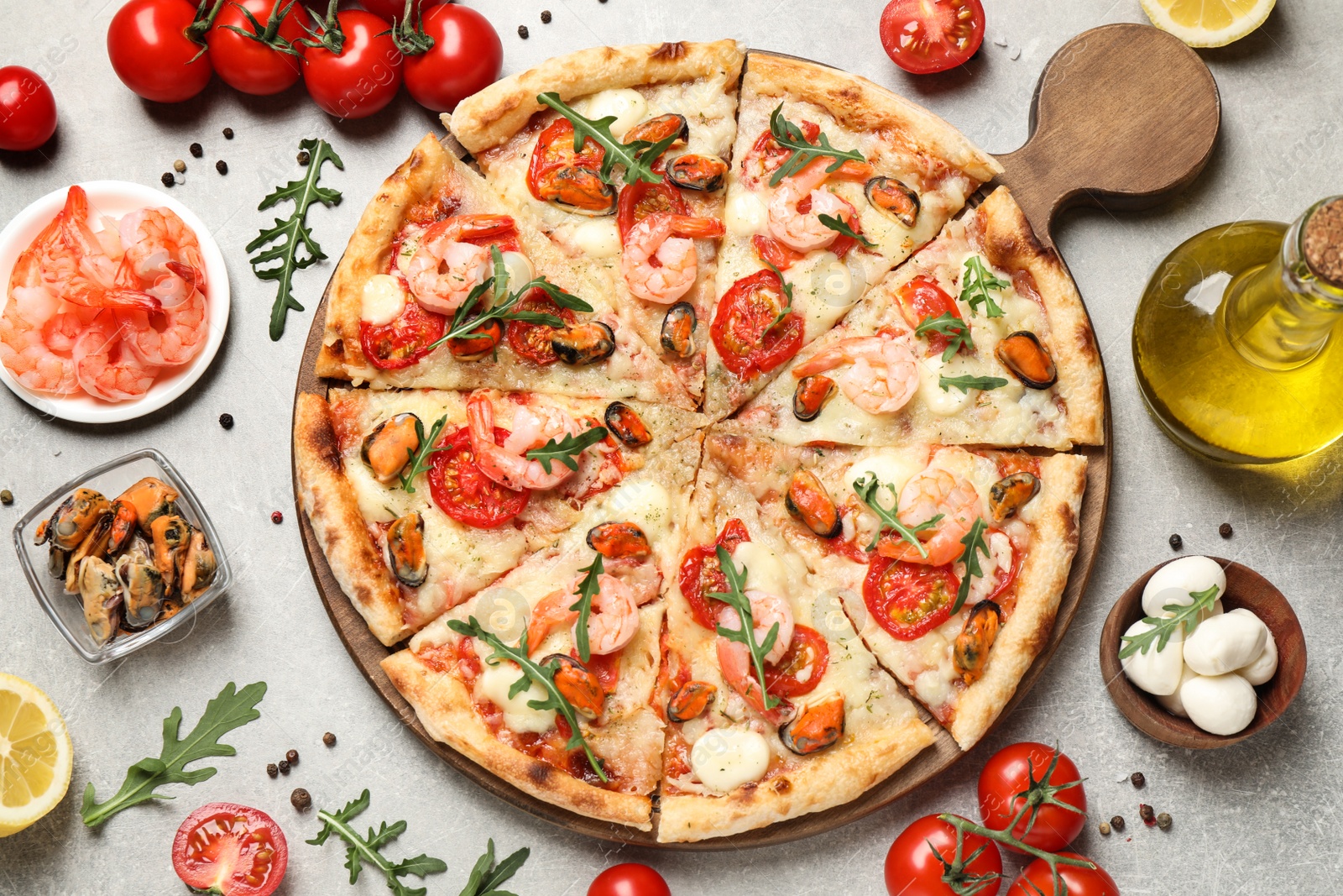 Photo of Delicious seafood pizza and fresh ingredients on light grey table, flat lay