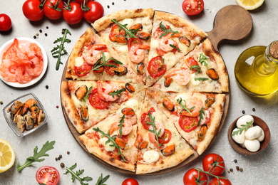 Delicious seafood pizza and fresh ingredients on light grey table, flat lay