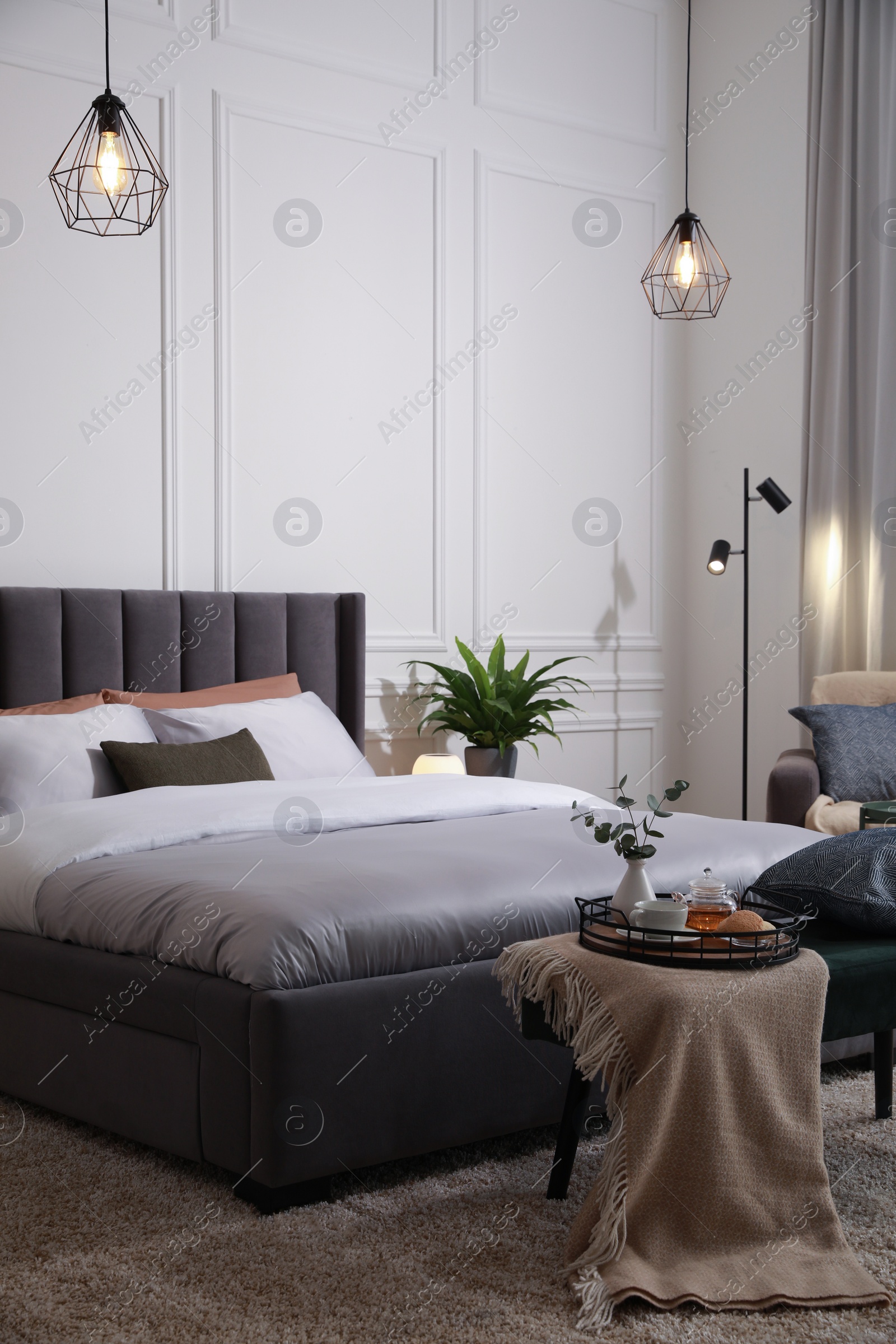 Photo of Stylish bedroom interior with large comfortable bed and ottoman