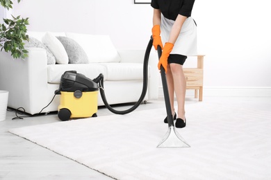 Woman cleaning carpet with vacuum cleaner, closeup