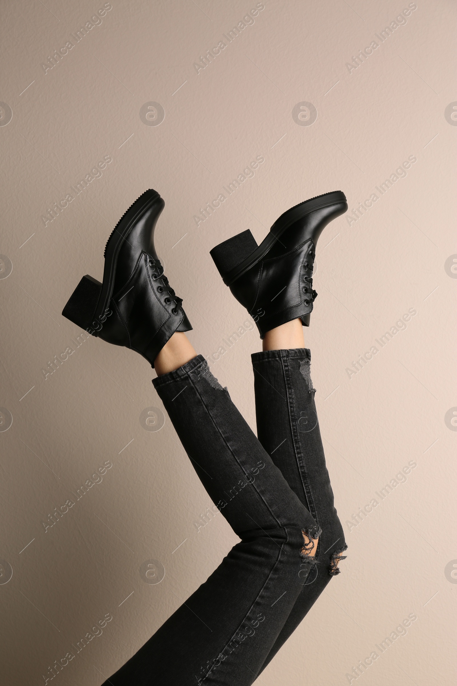 Photo of Woman wearing stylish boots on beige background, closeup