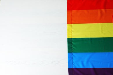 Photo of Rainbow gay flag on wooden background, top view with space for text. LGBT concept