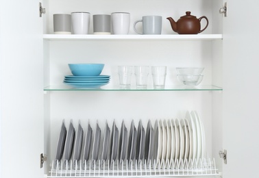 Photo of Open kitchen cabinet with different clean dishware