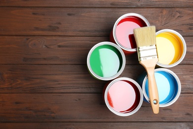 Flat lay composition with paint cans and brush on wooden background. Space for text