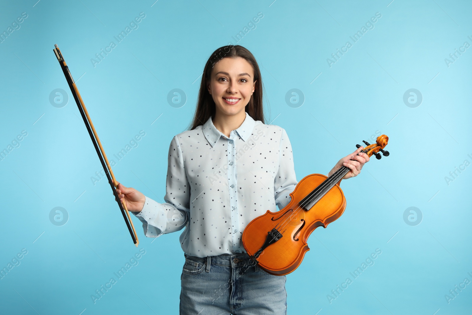 Photo of Music teacher with violin and bow on turquoise background