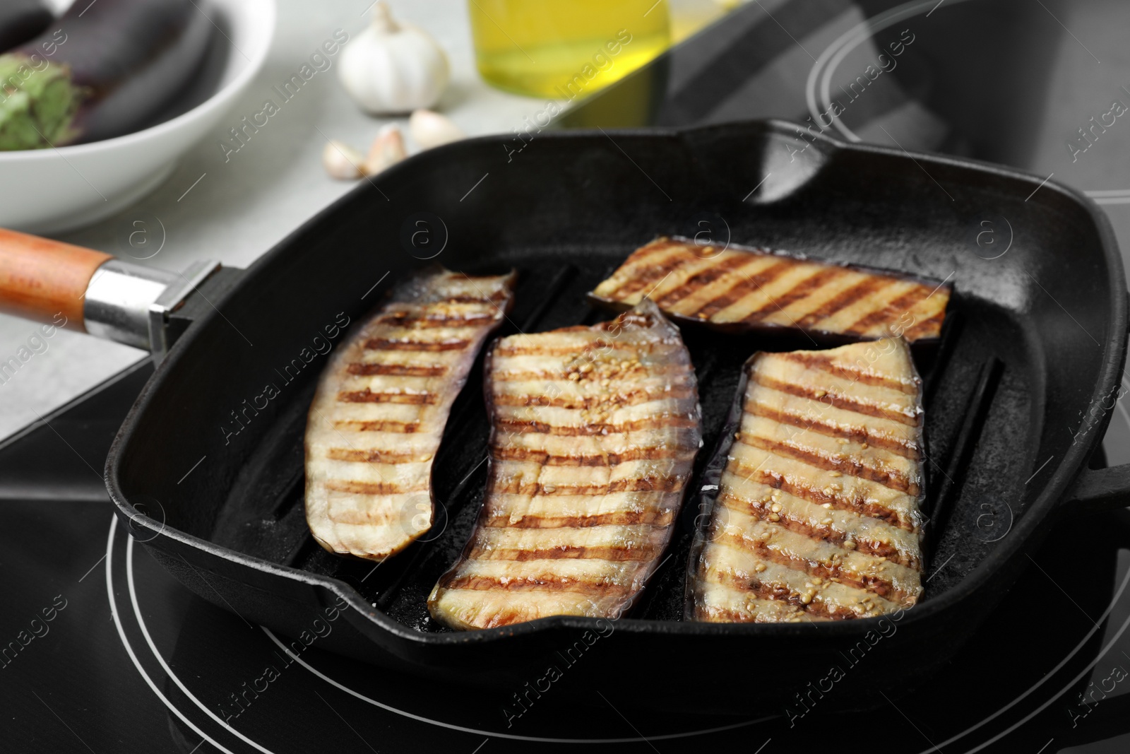 Photo of Delicious grilled eggplant slices in pan on stove, closeup
