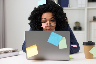Photo of Deadline concept. Tired woman working with laptop in office. Many sticky notes everywhere as reminders