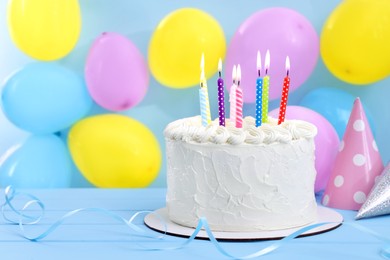 Photo of Delicious cake with burning candles and festive decor on light blue background. Space for text