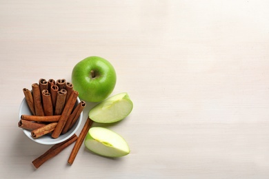 Fresh apples and cinnamon sticks on table, top view