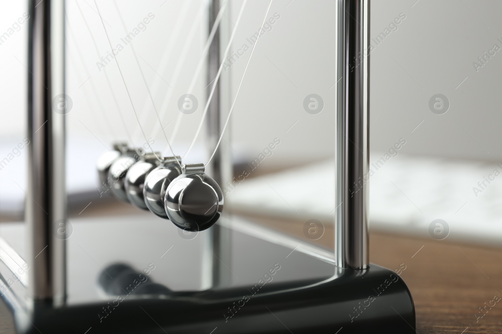 Photo of Newton's cradle on wooden table, closeup. Physics law of energy conservation