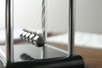 Newton's cradle on wooden table, closeup. Physics law of energy conservation