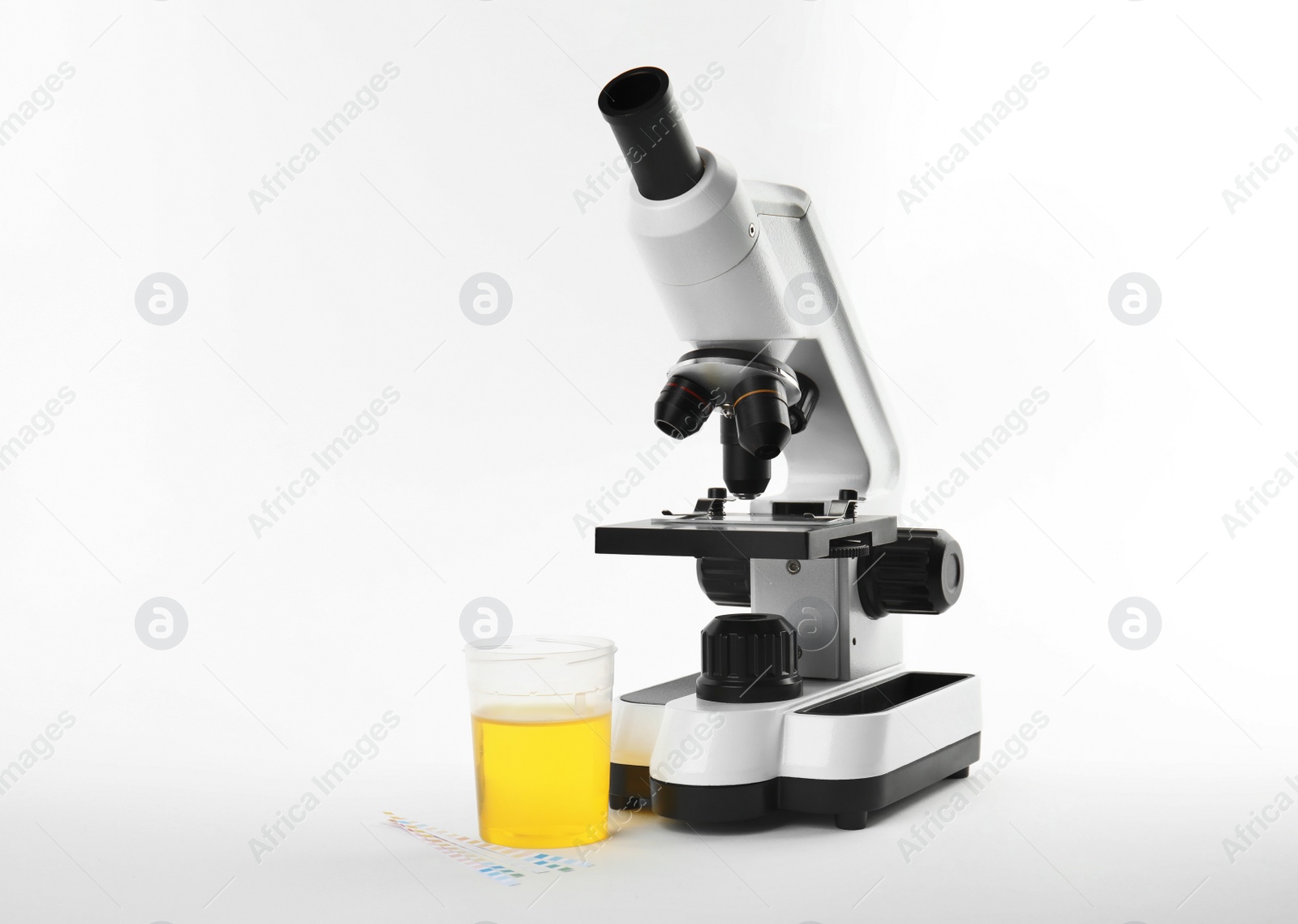 Photo of Laboratory ware with urine sample for analysis and microscope on white background