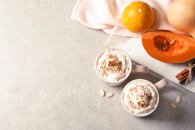 Photo of Flat lay composition with cups of tasty pumpkin spice latte and space for text on gray background