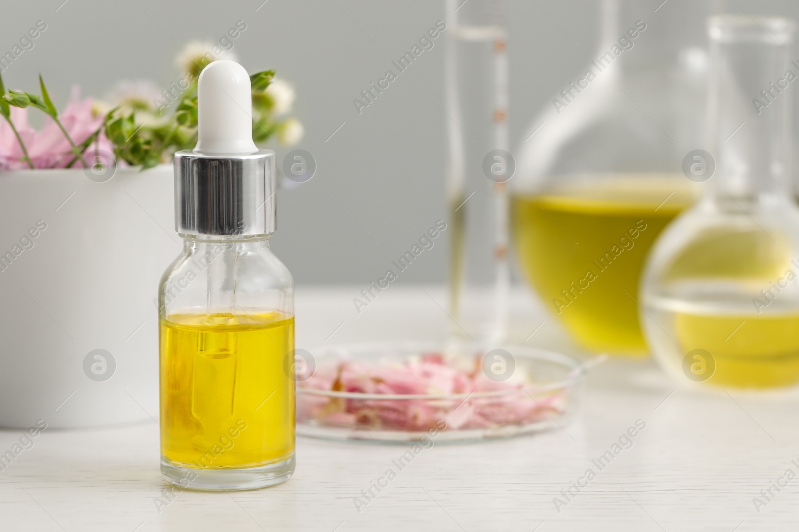 Photo of Bottle of cosmetic oil on white wooden table, closeup. Space for text