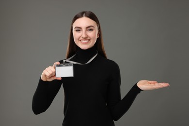 Happy woman with blank badge on grey background