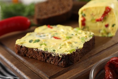 Photo of Tasty butter with green onion, chili pepper and rye bread on table, closeup