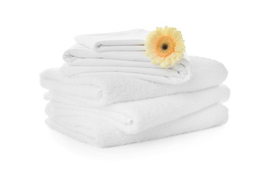 Stack of towels and bed sheets with gerbera on white background