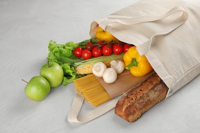 Different fresh vegetables and fruits in tote bag on light table